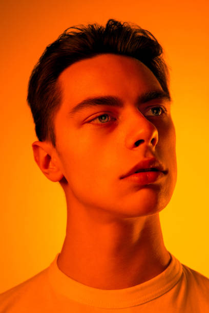 istock Handsome caucasian man's portrait isolated on orange studio background in neon light, monochrome 1297201905