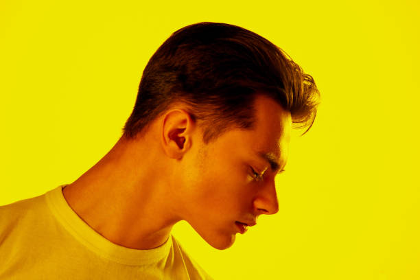 Handsome caucasian man's portrait isolated on orange studio background in neon light, monochrome