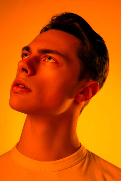 istock Handsome caucasian man's portrait isolated on orange studio background in neon light, monochrome 1297201947