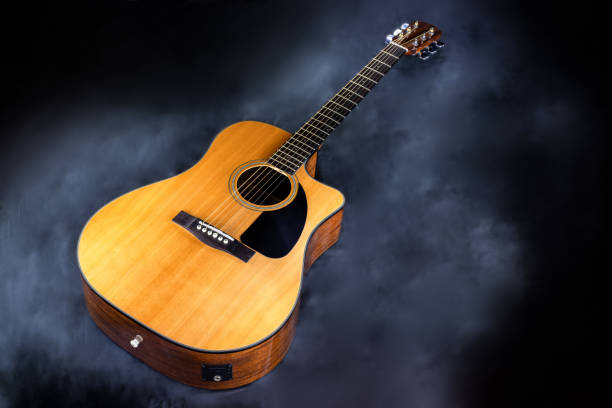 istock acoustic classical yellow six-string guitar with black pickguard in smoke on black isolated background 1297201993