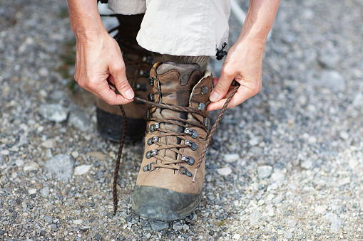 Hands of a senior woman tying hiking boots, boots are made for hiking in the mountains