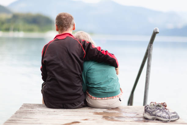 istock Senior couple sitting on jetty at a lake 1297203655