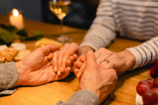 Close up shot of lover`s hands with engagement ring on romantic dinner table