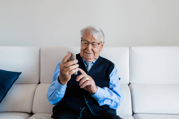 istock Old man with tie talking on the phone sitting on the couch 1297204463