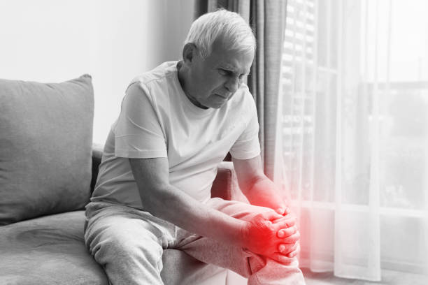 senior mann leidet unter schmerzen im knie zu hause. - arthritis senior adult rheumatoid arthritis sadness stock-fotos und bilder