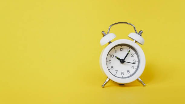 istock white analog  white clock on vivid yellow background for  time passing   , appointment ,schedule, time out or planning concept 1297205667