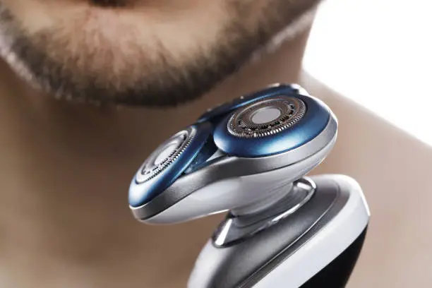 Closeup of male chin and modern electric shaver