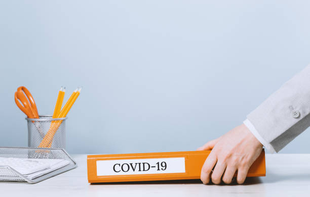 Covid-19 Coronavirus written on orange binder business paperwork Coronavirus. Covid-19 written on orange binder with business paperwork. Person in the office holding a folder. Copy space. Archive and documents. Filing and regulations during lockdown, back to office tabs ring binder office isolated stock pictures, royalty-free photos & images