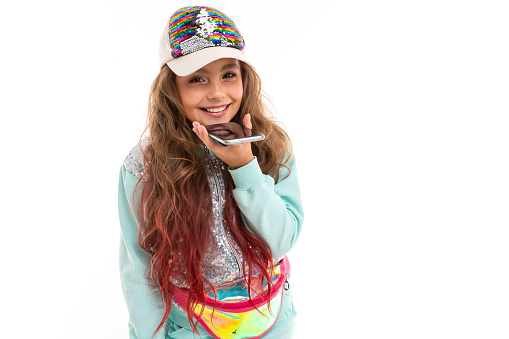 Little beautiful caucasian girl with long wavy chestnut hair and nice smile in traksuit and a cap smiles