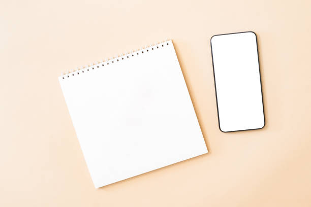 istock Flat Lay mockup of smartphone with blank screen, white notepad on color background 1297210303