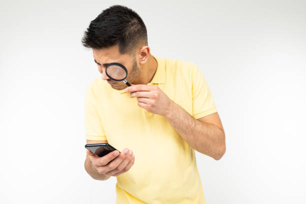 istock handsome man with low vision holds a magnifier and a smartphone in his hand on a white background with copy space 1297210740