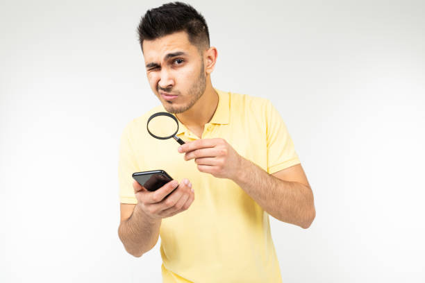 istock handsome man with low vision holds a magnifier and a smartphone in his hand on a white background with copy space 1297210752
