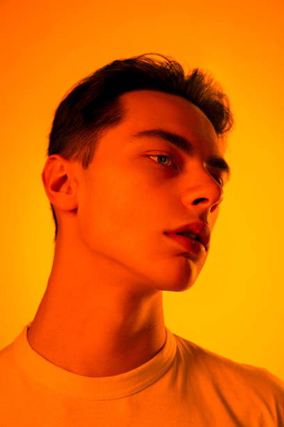 istock Handsome caucasian man's portrait isolated on orange studio background in neon light, monochrome 1297210845