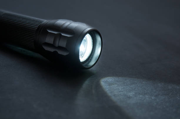 istock Flashlight with beam of light close up on black background 1297212376