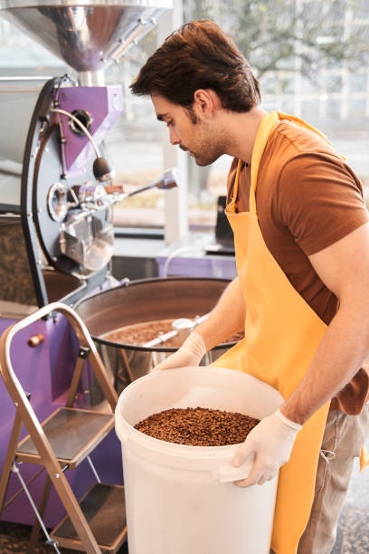 istock Man holding heavy bucket with coffee beans 1297212946