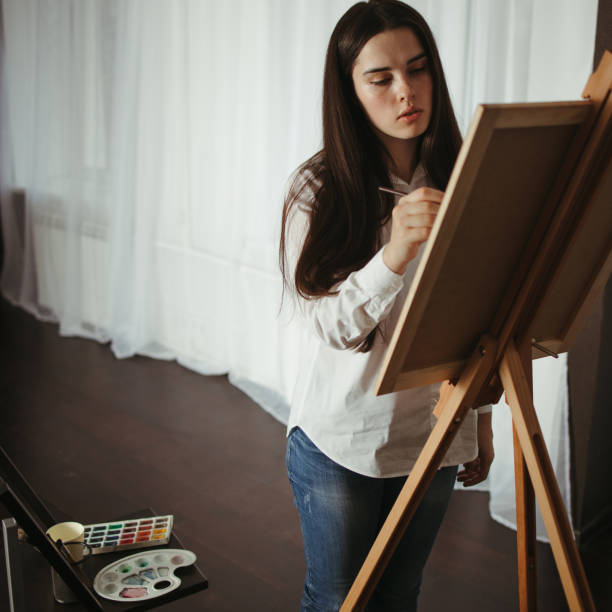 istock Young concentrated woman do easel drawing 1297213331