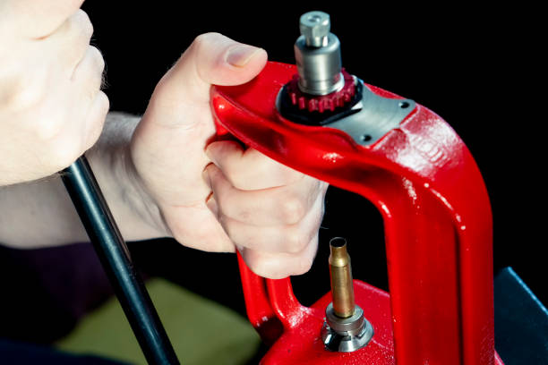 istock Red hand press and ammo shell against dark background, soft focus. Copy space. The process of making a rifle cartridge 1297215017