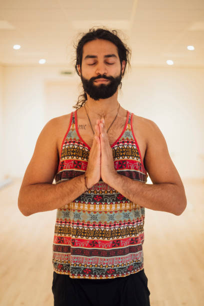 Finding Inner Peace Waist up view of a man doing yoga during lockdown in the Covid 19 pandemic. He is standing with his hands together in prayer pose and his eyes are closed. yoga instructor stock pictures, royalty-free photos & images