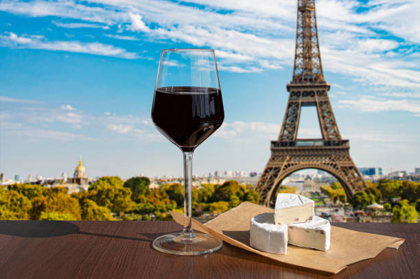 Glass of wine with brie cheese on Eiffel tower and Paris skyline background stock photo