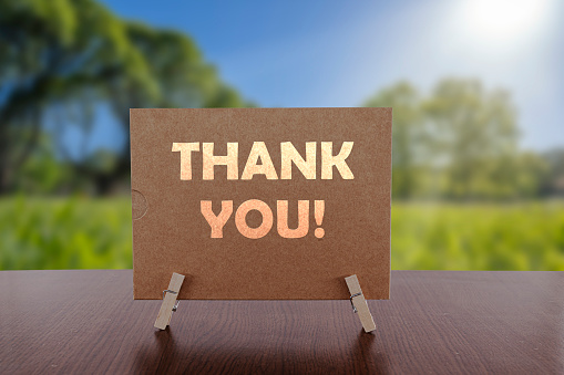 Thank you card on the table with sunny green park background.
