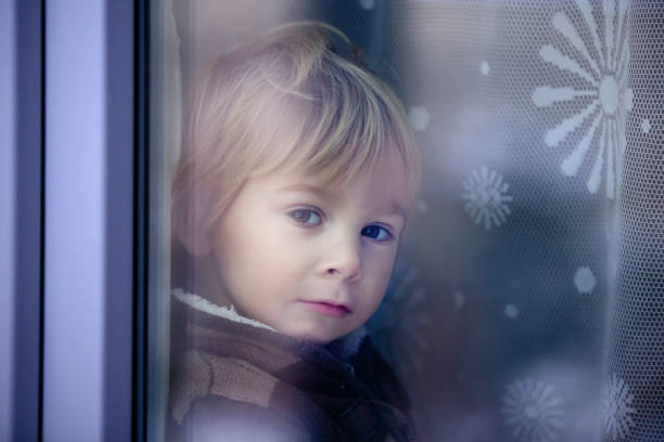 istock Little toddler boy, sitting behind the window, 1297220730