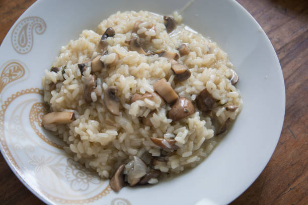 "Risotto ai funghi",cooked rice dish with slices of Common Mushrooms in a white bowl stock photo