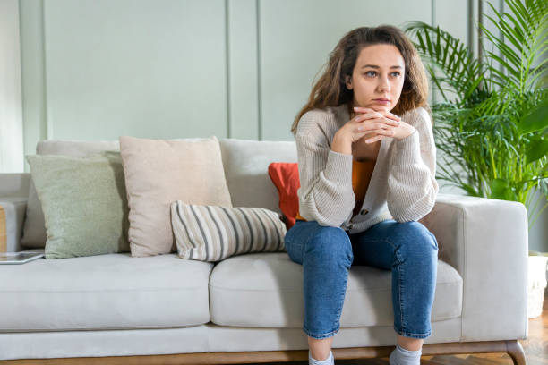 istock Depressed young woman on sofa at home 1297221240