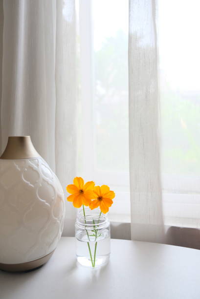 istock Orange flowers on the table near window. 1297222665