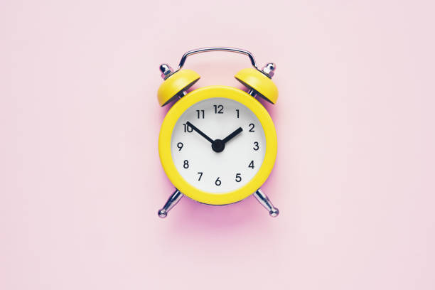 istock Yellow vintage alarm clock on a pink background. Daylight saving concept. Flat lay, copy space. 1297224521
