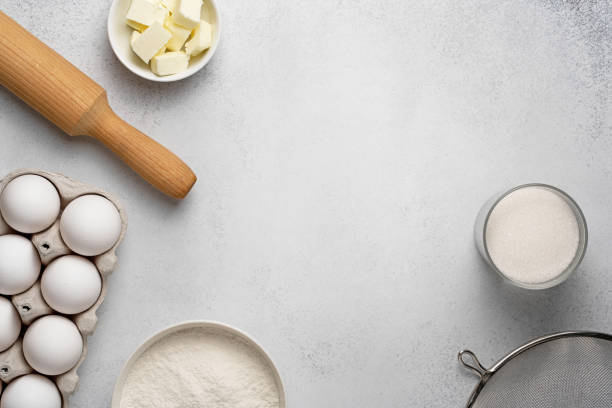 istock Wheat flour, sugar, sieve, rolling pin, butter and white eggs on grey background 1297225560