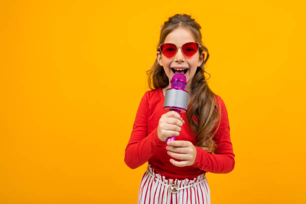 istock cute european girl singing into a microphone on a yellow background 1297226501