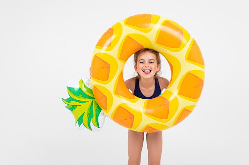 sweet girl about to swim in the sea with a rubber ring and a mattress on an isolated white background.