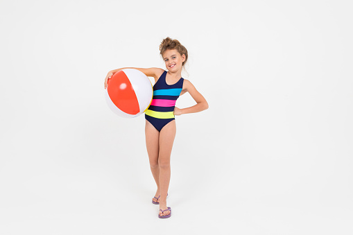 teenager girl in a swimsuit with a swimming ball on an isolated white background with copy space.