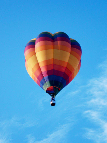 Hot Air Balloon in mid-air with blue sky background Multi-coloured hot air balloon rises in mid-air with a blue sky background - UK bristol england stock pictures, royalty-free photos & images