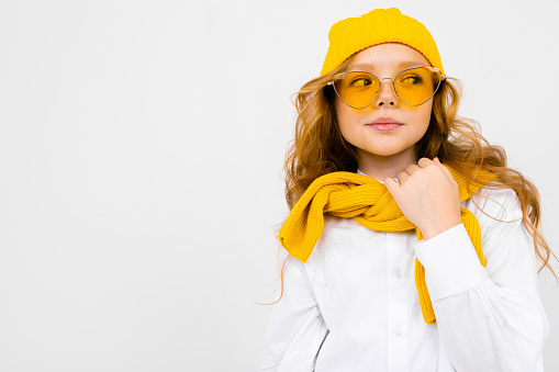 romantic teenager girl with yellow retro glasses and with a yellow hat and scarf on an isolated white background with copy space.