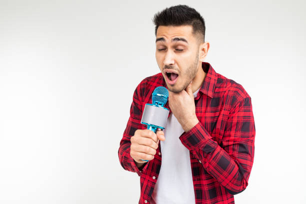 presentatore maschio con un microfono tra le mani ha mal di gola su uno sfondo bianco isolato studio - male singer singing men foto e immagini stock