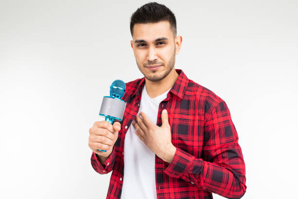 presentatore maschio con un microfono tra le mani ha mal di gola su uno sfondo bianco isolato studio - male singer singing men foto e immagini stock