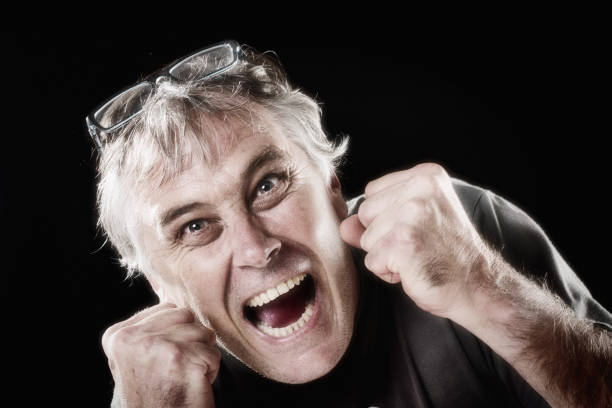 Man punches the air, either full of joyful surprise or furious rage Middle-aged man bunches his fists with an animated expression on his face. punching one person shaking fist fist stock pictures, royalty-free photos & images