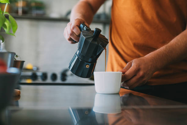 istock Anonymous Young Man Pouring Steaming Coffee into a Mug on a Kitchen Counter 1297236836