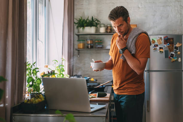 istock Handsome Young Man Making a Meal while Watching a Live Cooking Session in a Kitchen 1297236853
