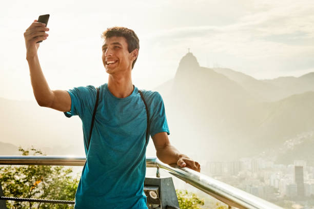 Tourist taking selfie Happy young man standing in a viewing deck with Christ the Redeemer in background and taking selfie cristo redentor rio de janeiro stock pictures, royalty-free photos & images