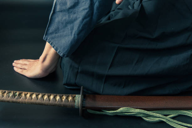 um homem sentado faça um arco ao lado de sua espada. - blade war traditional culture japanese culture - fotografias e filmes do acervo