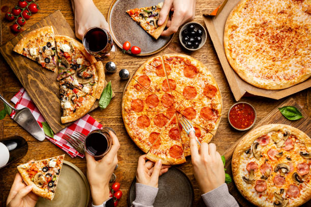 Different tipes of pizza Family or friends pizza party. Flat-lay of people eating different types of pizza and drinking red wine over rustic wooden table, top view. pizza stock pictures, royalty-free photos & images