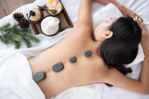 View of Asian Woman Receiving Rock Therapy Massage in Spa