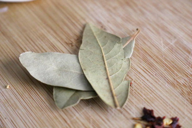 istock Dried Bay Leaves on a Wooden Cutting Board 1297249783