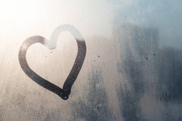 Frozen window with hand written heart and morning sunlight