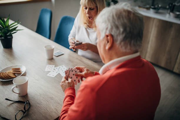 istock Senior couple having fun playing cards at home 1297251993