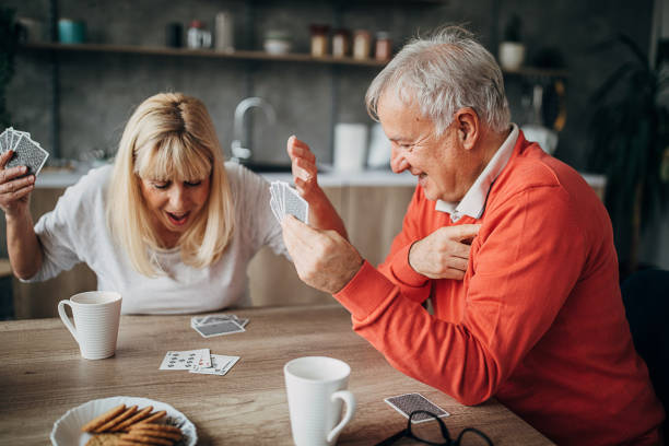 istock Happy senior couple having fun playing cards at home 1297253140