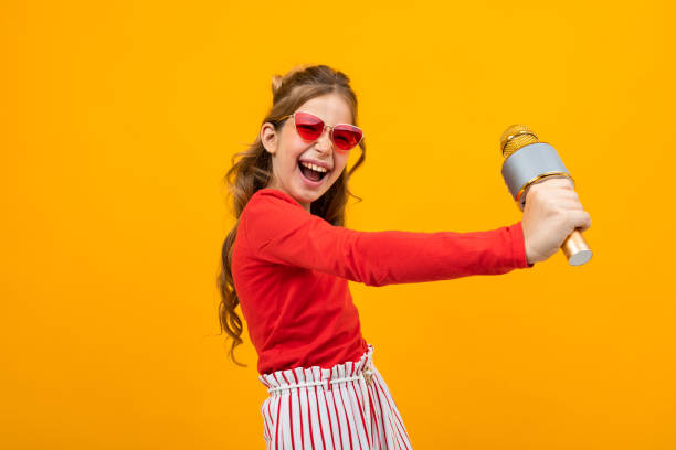istock young singer with a microphone in her hands on a yellow studio background 1297253716