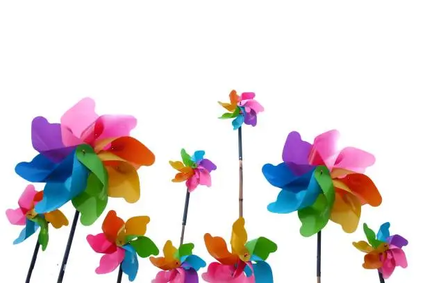 Photo of A group of multicolored a garden windmill with colorful wind spinners on white isolated backdround with copy space